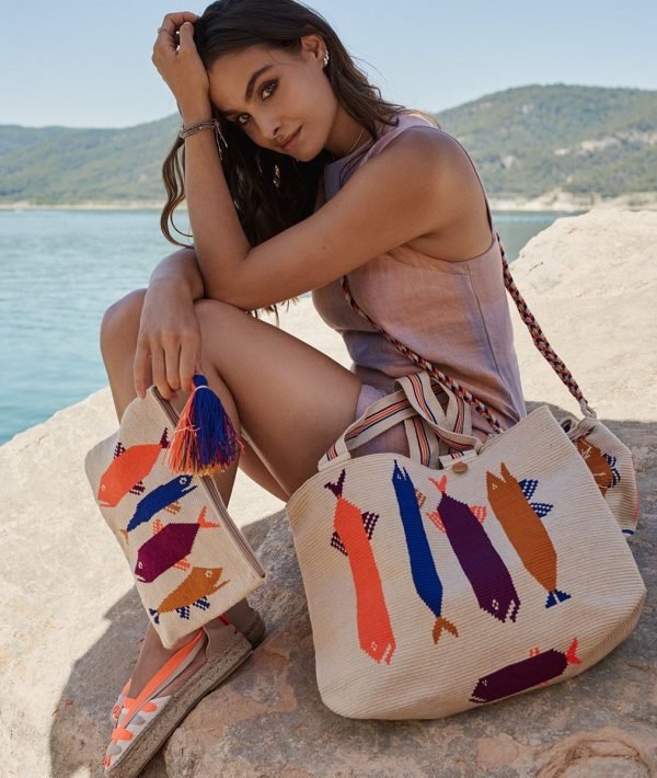 Woman using a wayuu clutch bag with goldfish design